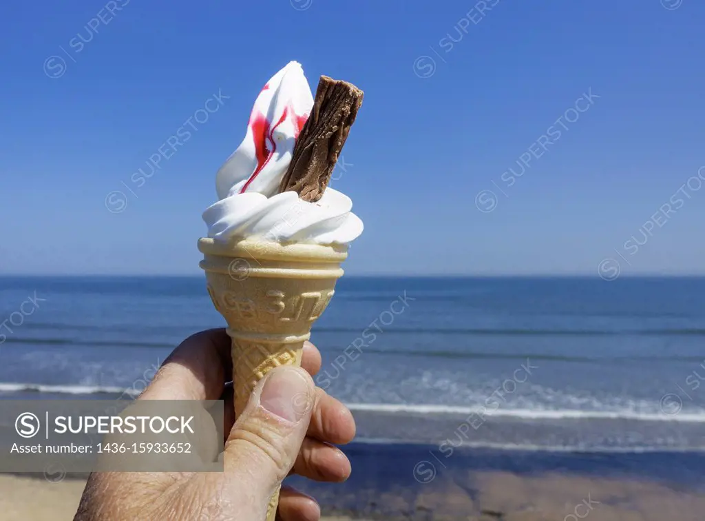 Ninety Nine ice cream cone with raspberry against blues sky and sea. north east England, UK.