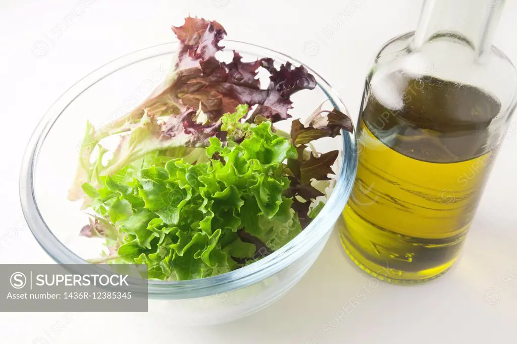 Mixed Red and Green Multileaf Lettuce Leaves in a Glass Bowl with Extra Virgin Olive Oil.