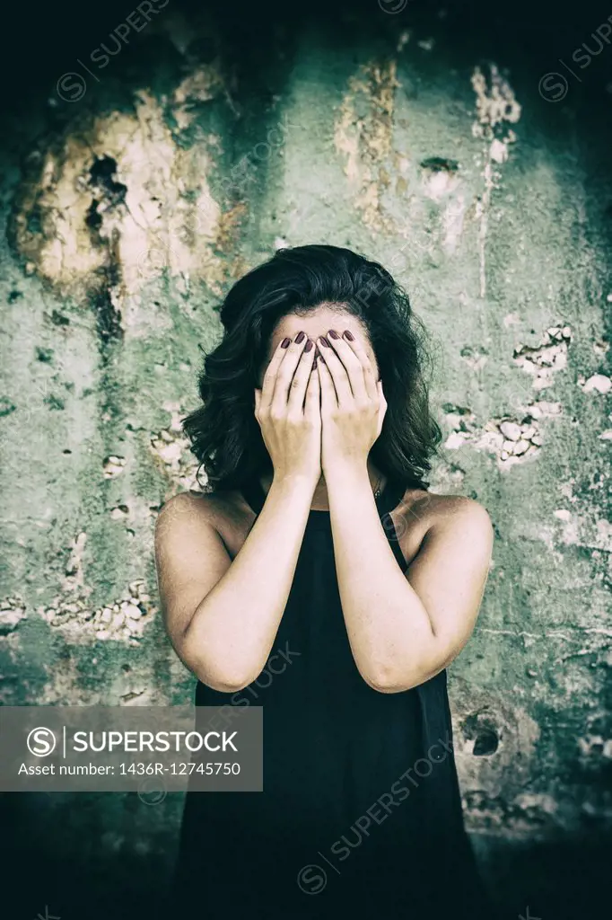 Scared woman hiding face with hands.