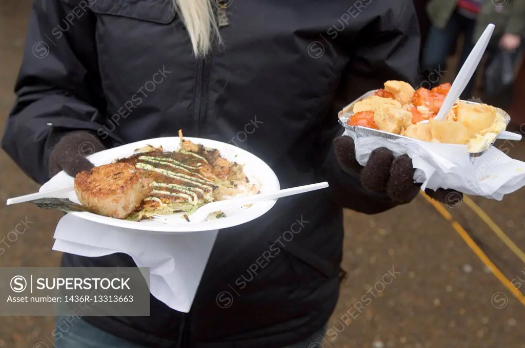 Woman with gloves holding plastic plates with food, on the street