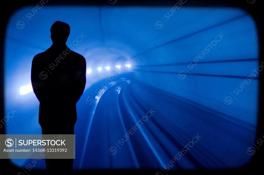 silhouette of a man walking through a train tunnel.
