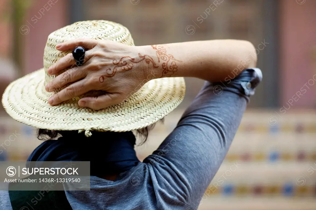 Portrait of a mature caucasian woman with hat and brown hair in position of rest and relaxation with a henna tattoo on her hand.