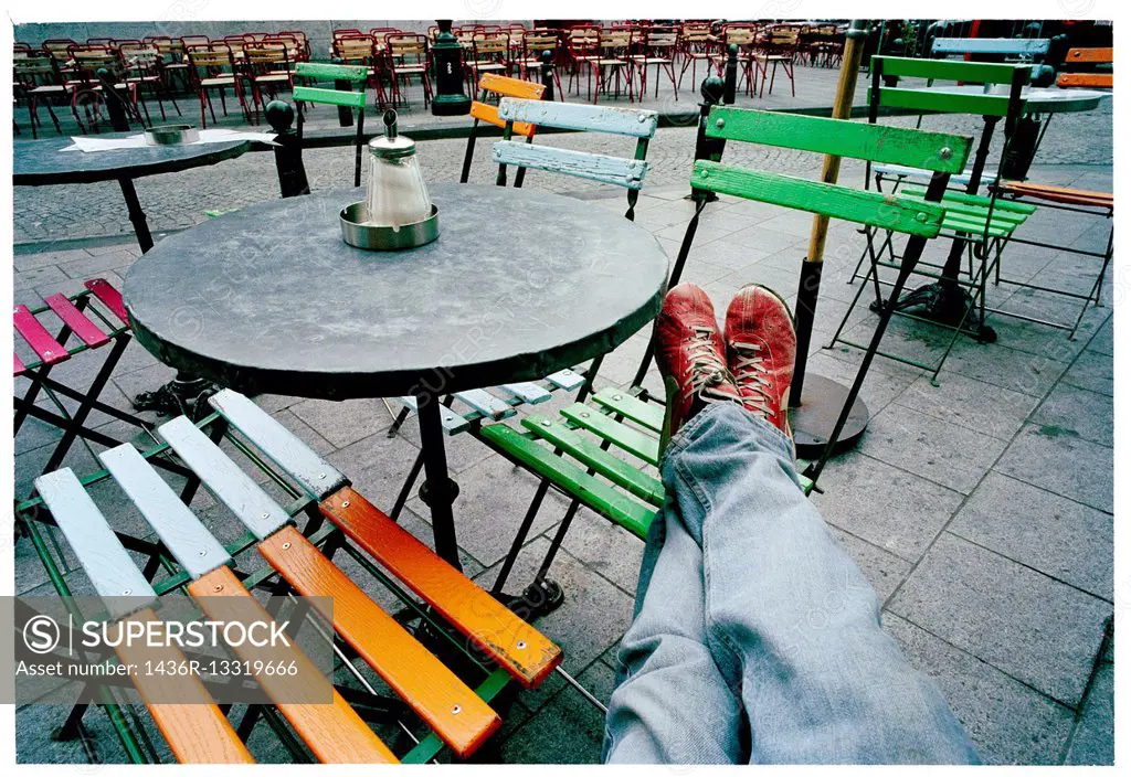 a man with his feet on top of a chair in a terrace of a bar in a relax position.
