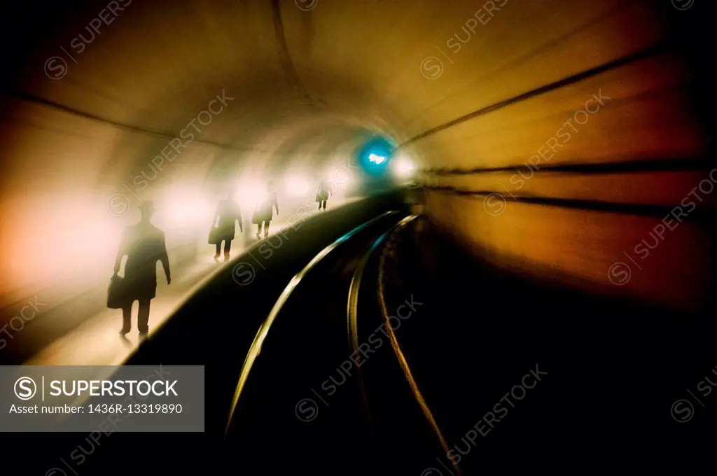 silueta de un hombre andando por un tunel de un tren. , silhouette of a man walking through a train tunnel.