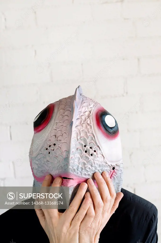 Young woman with a fish mask with a hands in her face with a surprise expression.