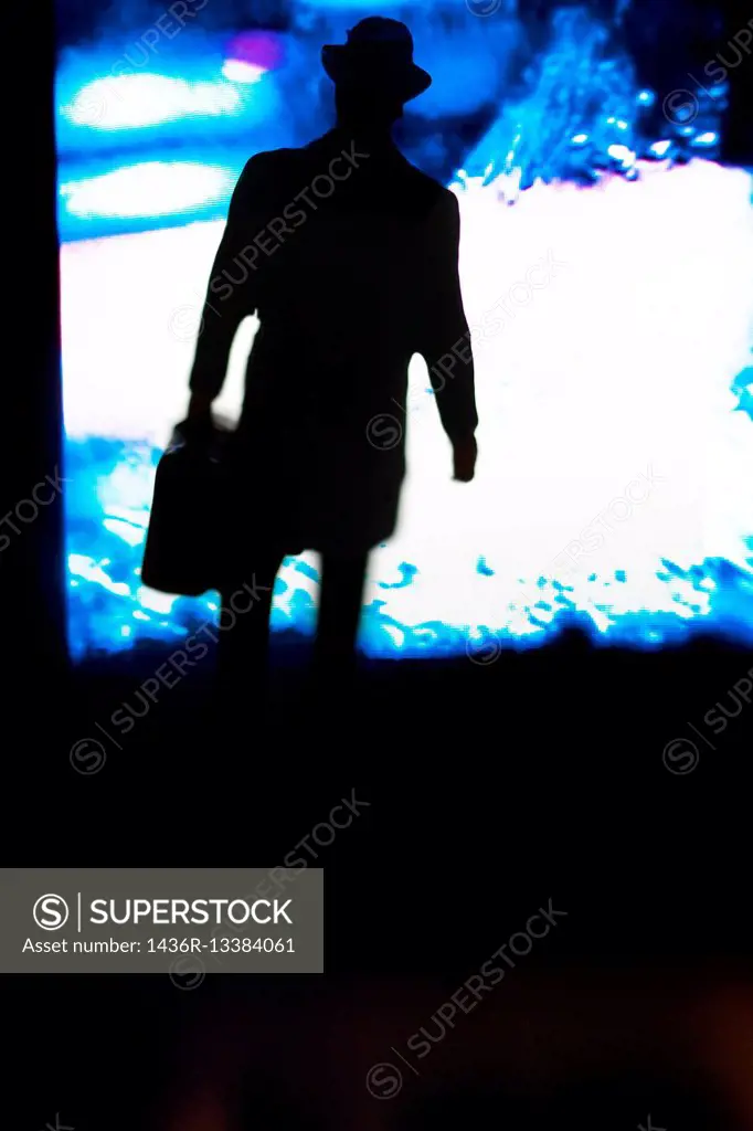 Silhouette of a unrecognizable and incognito man with a executive briefcase on a color background.