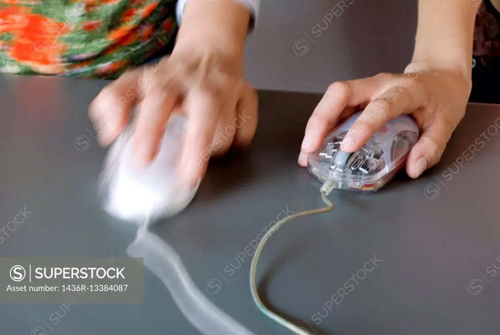 hands of two young people with two computer mouse in a working desk.