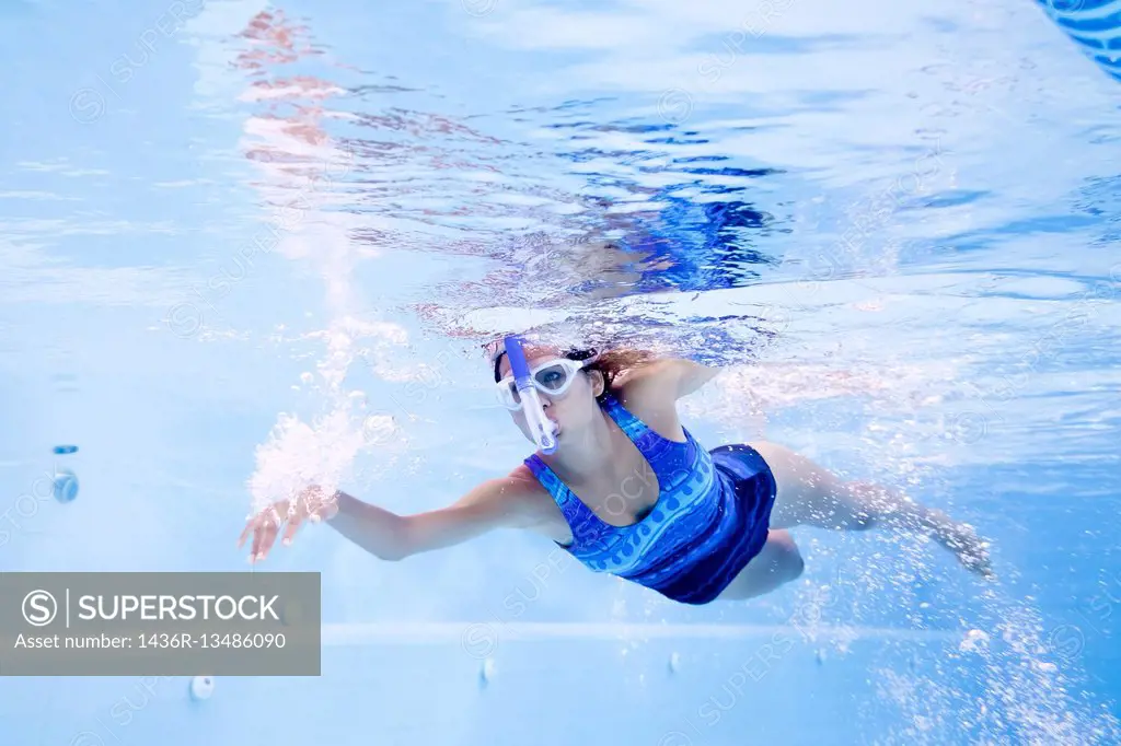 Young woman practicing swimming in lap pool with swimmer snorkel and googles.