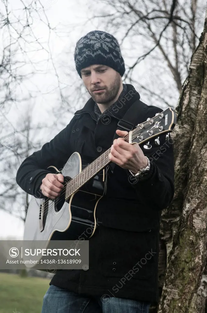 Man playing his guitar outdoors.