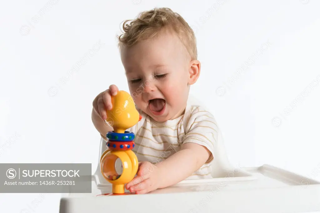 Little boy playing with a plastic rattle doll