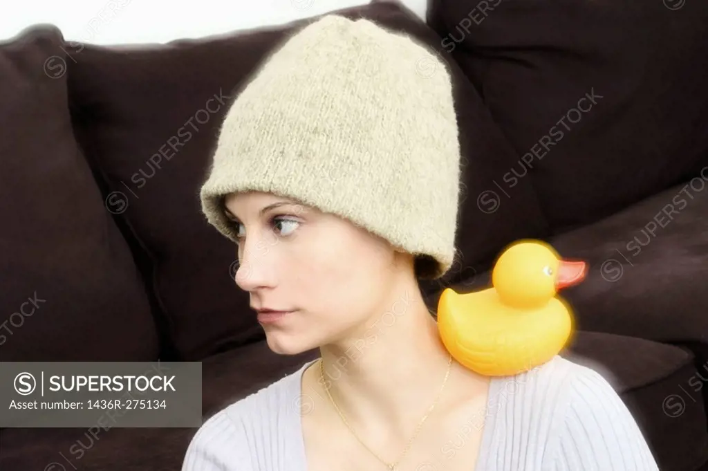 Young woman, wearing a hat, with a yellow rubber duck resting on her shoulder