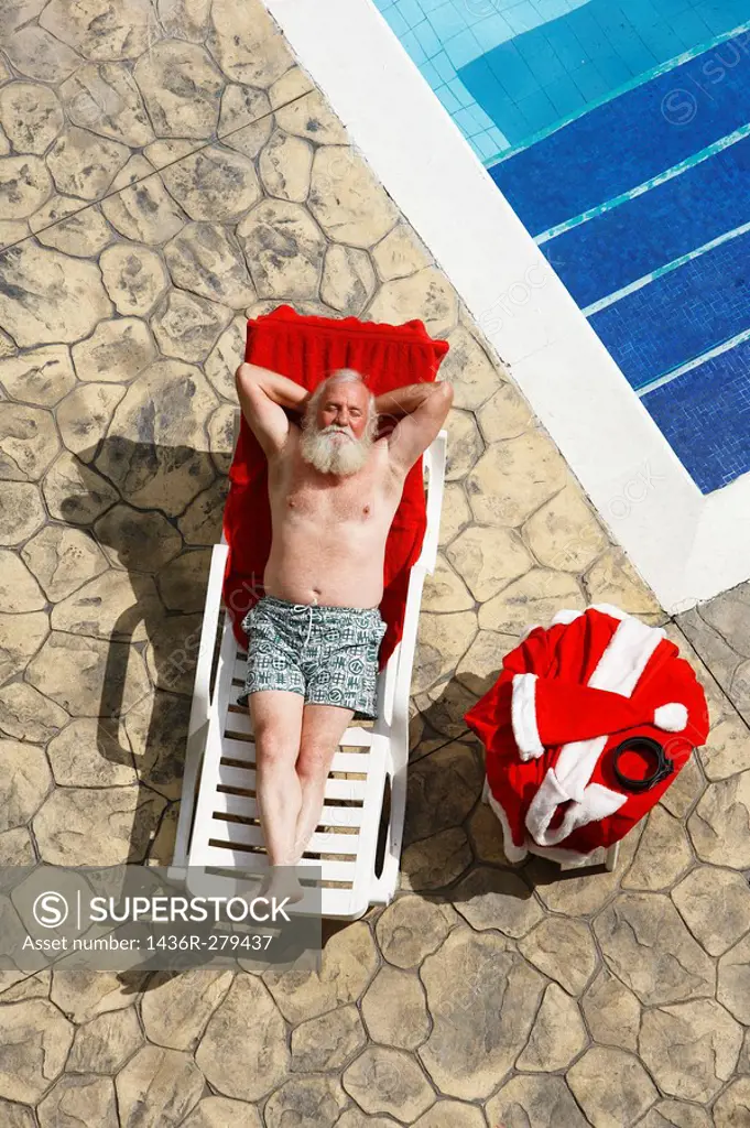 Santa relaxes on the side of a swimming pool