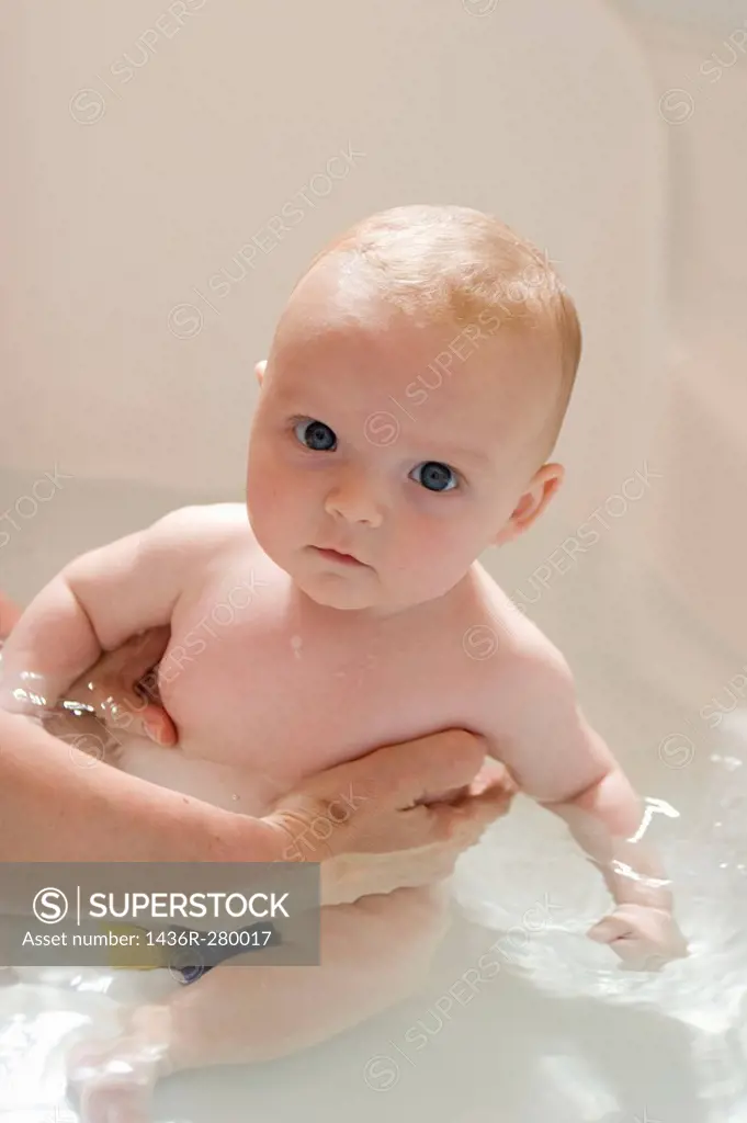 8 week old baby inthe bath looking into camera with a very serious expression