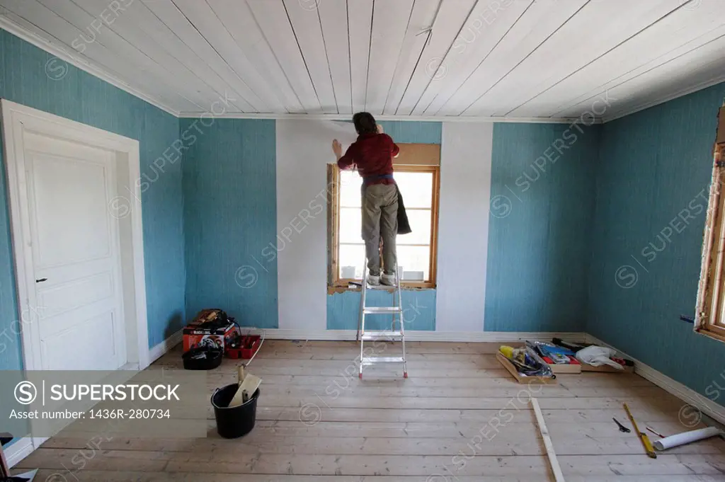Woman repapering a room. Paperhanger, wallpaper, renovation. Sweden, Scandinavia, Europe