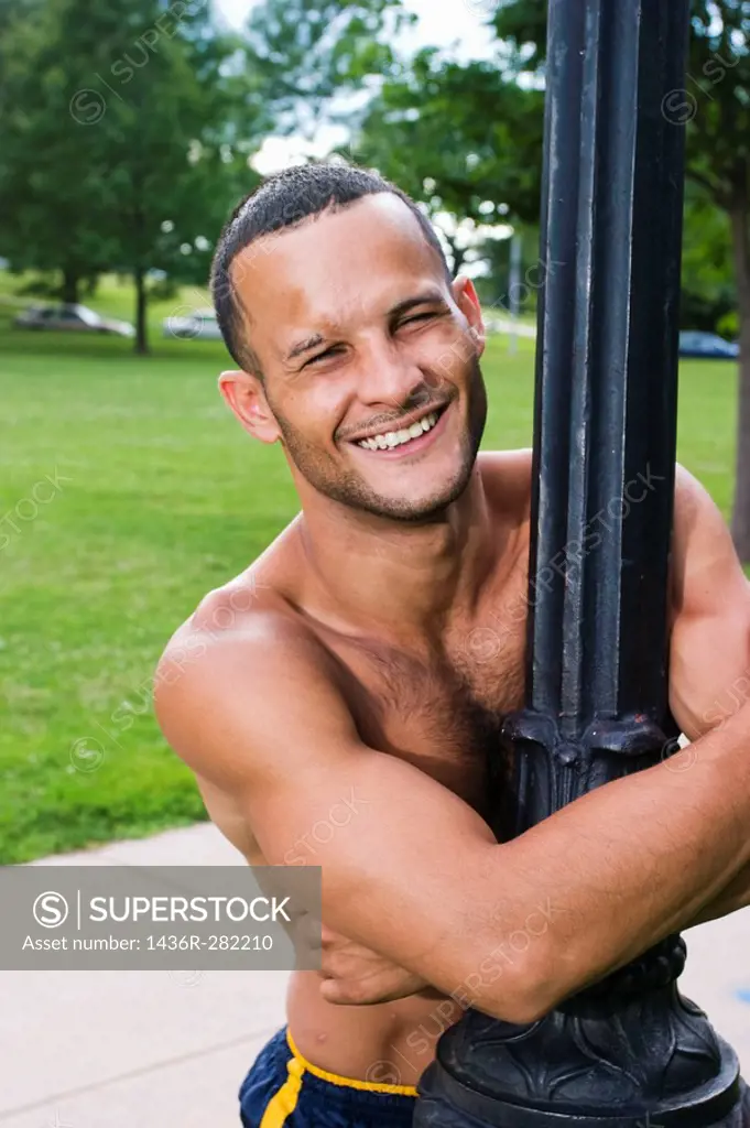 Young shirtless Hispanic man standing in a fight stance on the grass at a park
