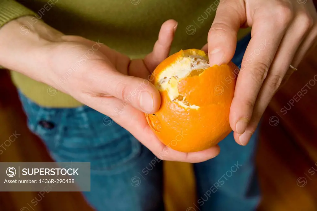 Close-up of a young woman´s hands as she peels an orange.