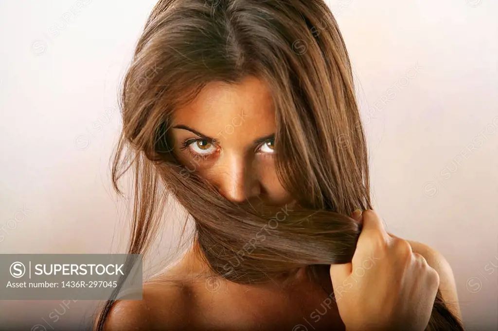 Studio Shot of girl covering her face with her long hair.