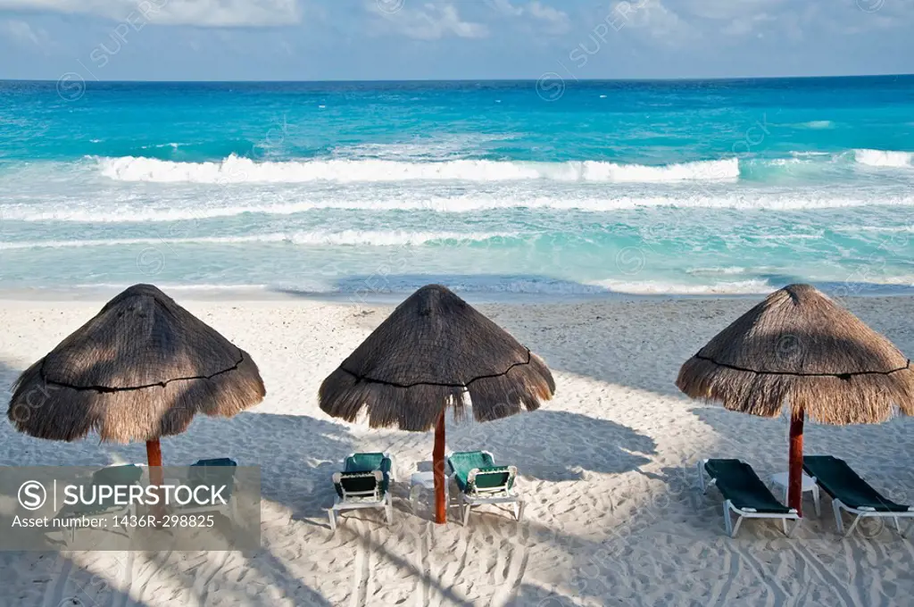 Three straw sun umbrellas on a white sandy beach