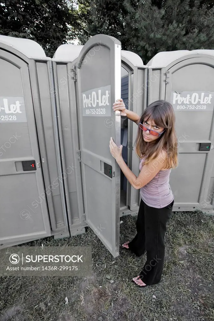 Young woman about to enter a portable toilet