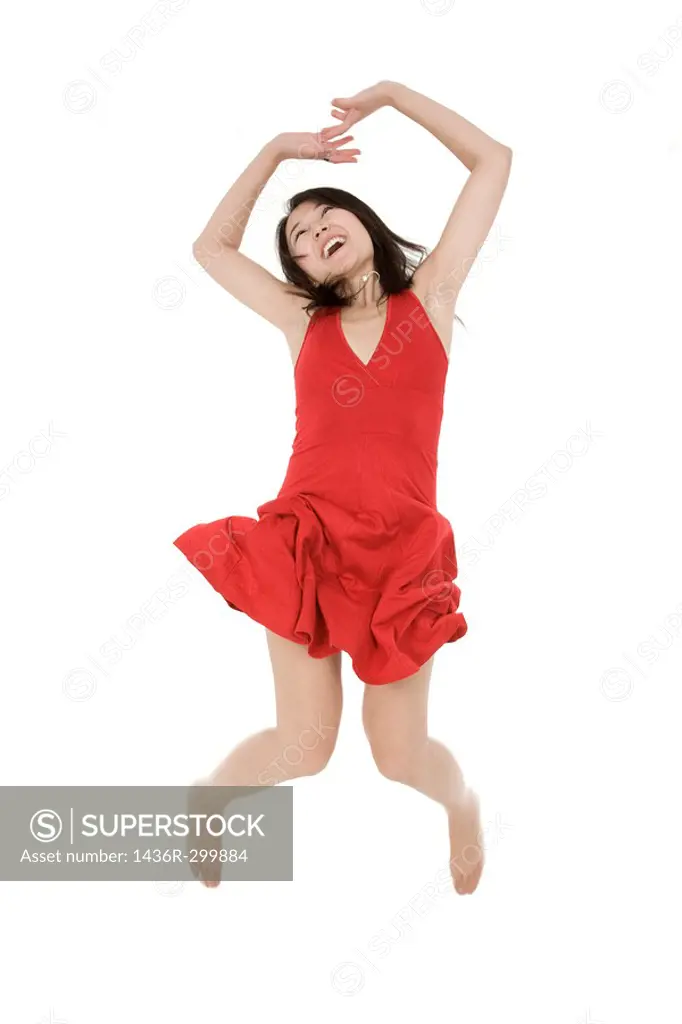 Beautiful Asain woman in a red sundress jumping on a white background