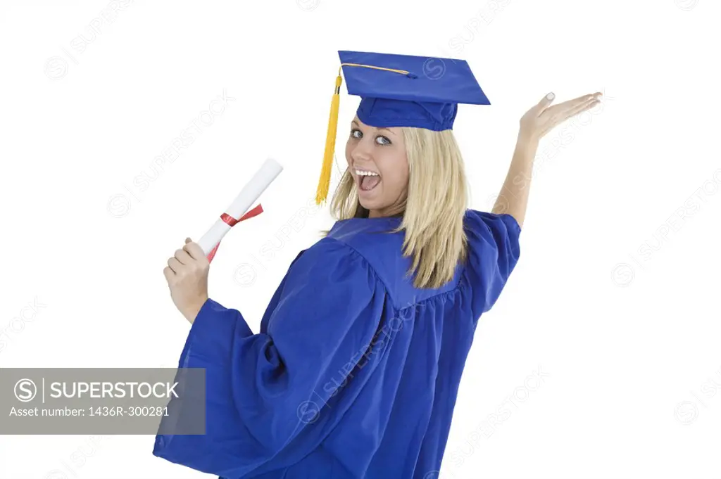 A female caucasian with blond hair standing in blue graduation gown and smiling  She is on a white background