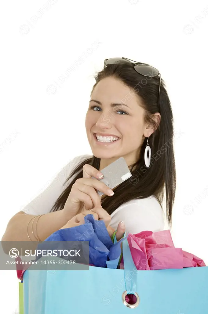 Excited Caucasian woman holding shopping bags and a credit card smiling on white background