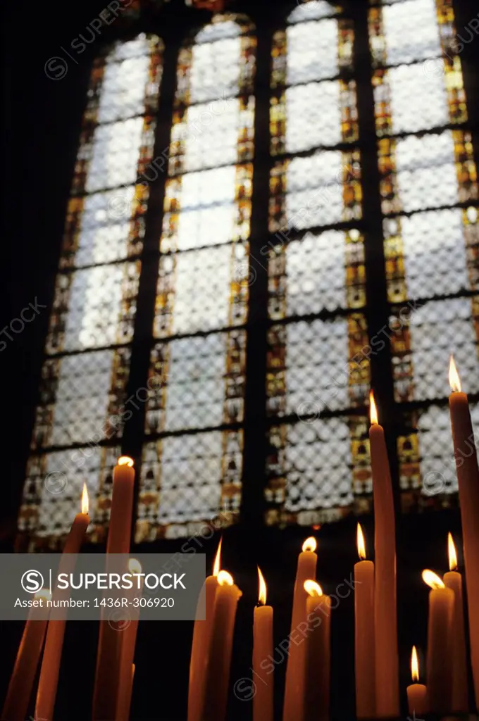 Candles burning in front of a stained glass window in the Auch Cathedral, Auch, France.