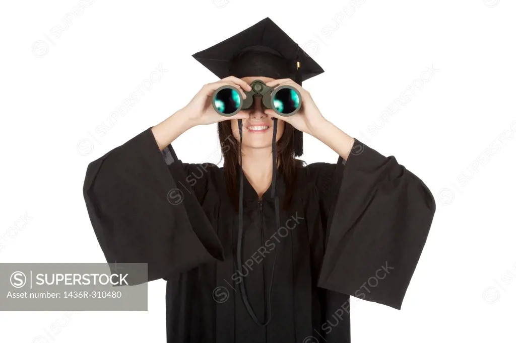 Beautiful Caucasian woman wearing in a black graduation gown and looking through binoculars