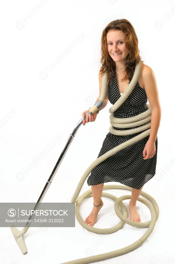 Young woman homemaker tangled in vacuum cleaner hose on white background