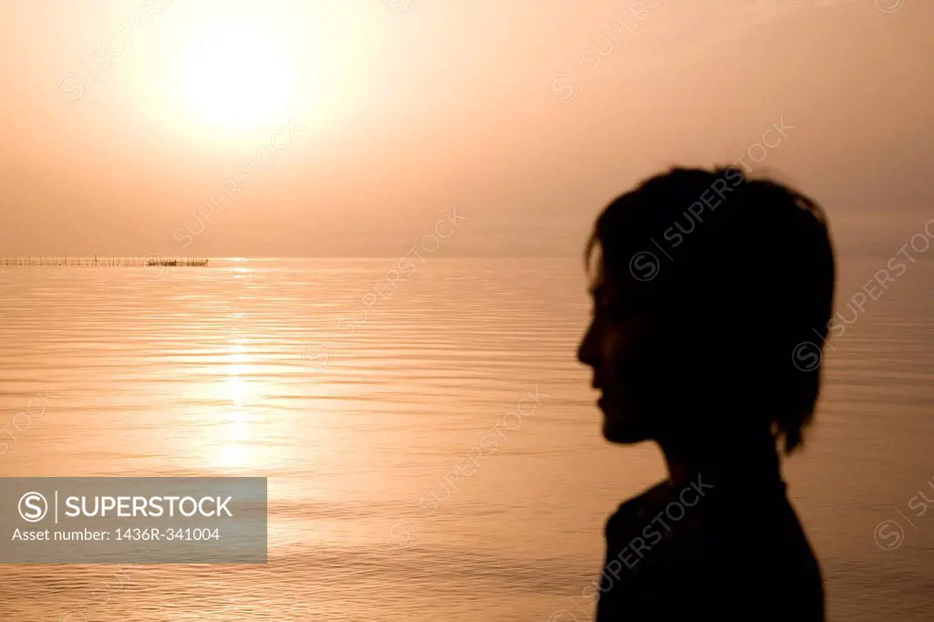 Silhouette of young woman looking at lake