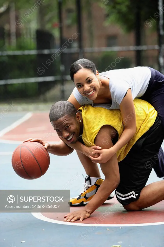 African-American girlfriend and boyfriend playing basketball