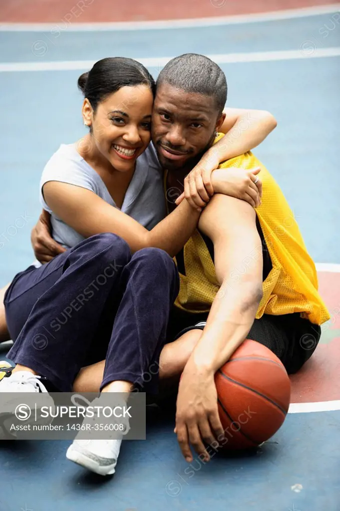 African-American girlfriend and boyfriend hugging and smiling into camera