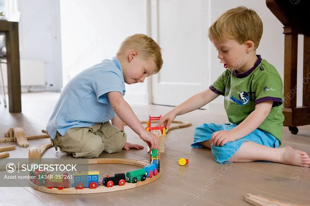Two little boys playing with a wooden train