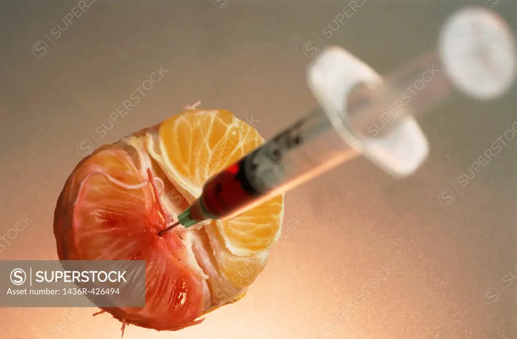 Syringe needle jabbed into a mandarin showing the possibility of genetically modified food