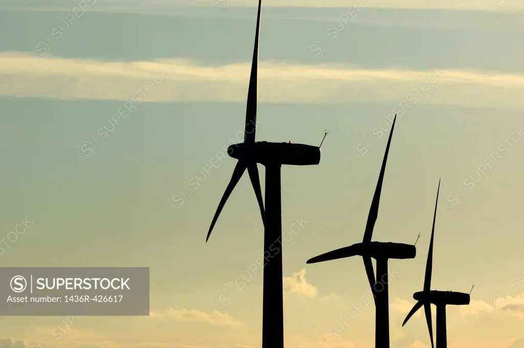 Silhouetted wind turbines against a cloudy sky, Donzere, Drome, France