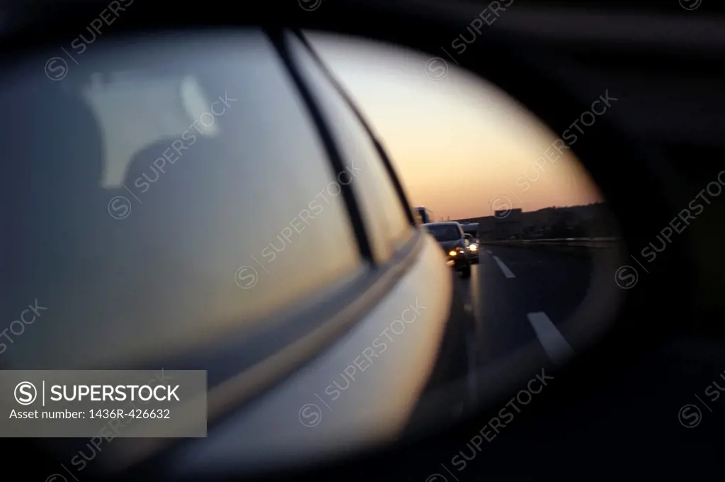 Left side rear view mirror reflecting traffic on the highway