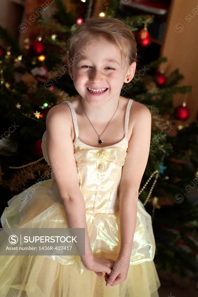 Little girl in a princess costume next to a Christmas tree