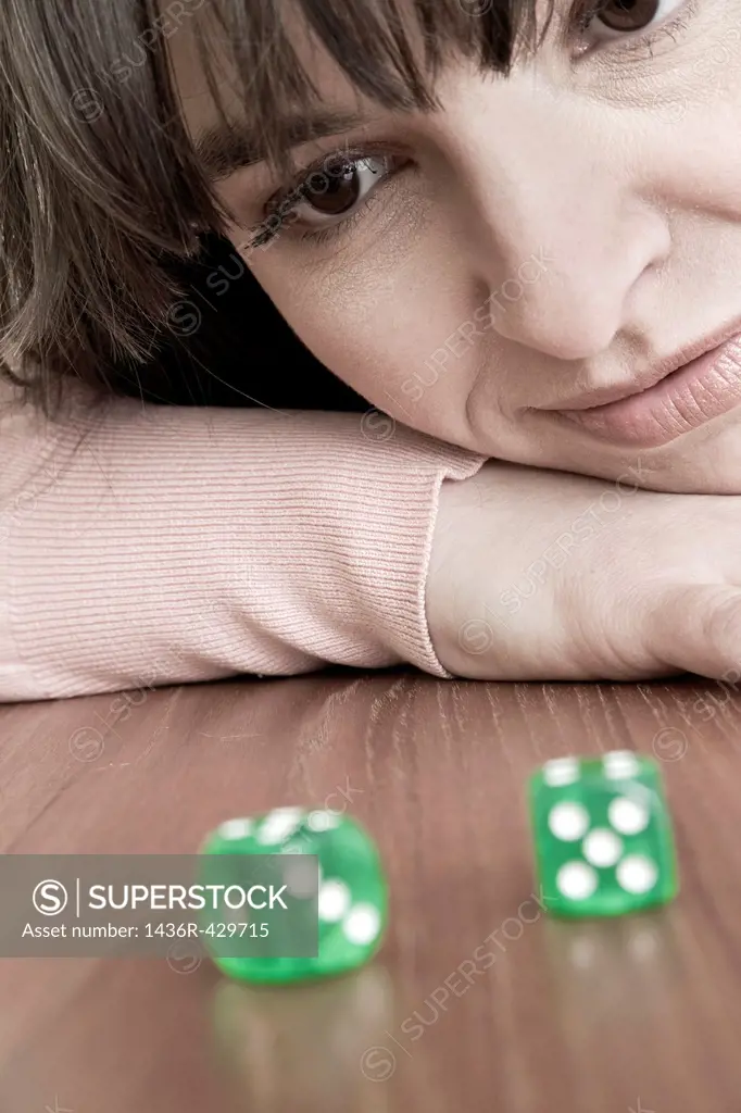 Young woman looking at a pair of green dice
