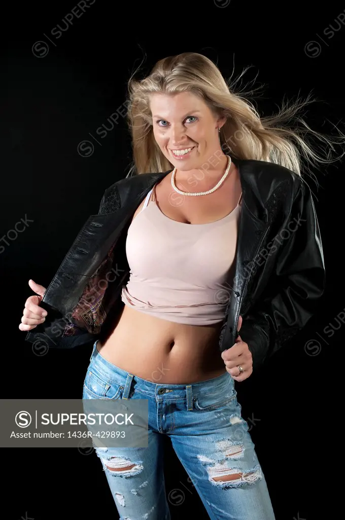Attractive woman in leather jacket posing on black background