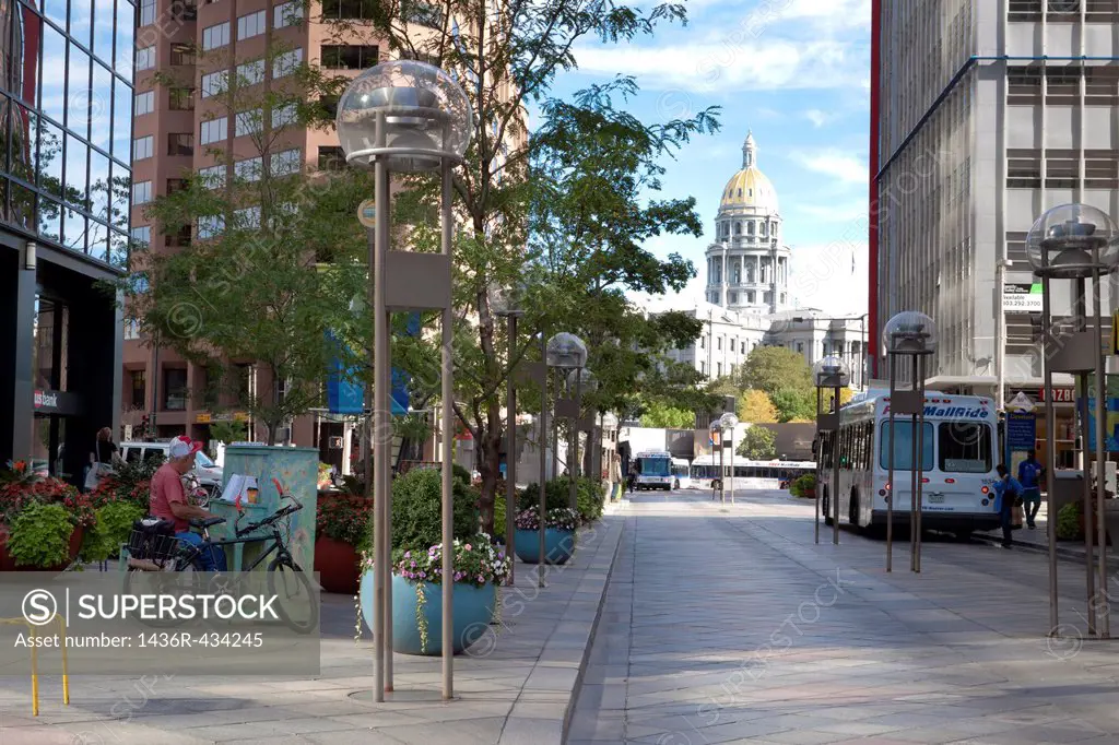 16th Street Mall in downtown Denver, Colorado with state capitol building and man playing painted piano on sidewalk