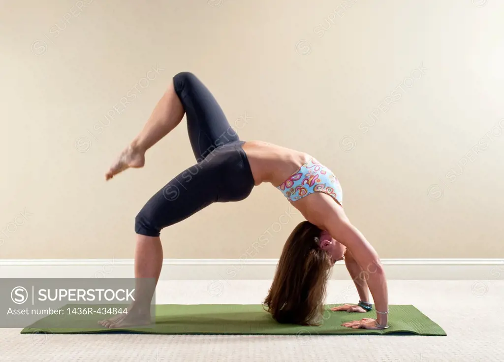 37 year old brunette woman doing a yoga pose in a home interior setting