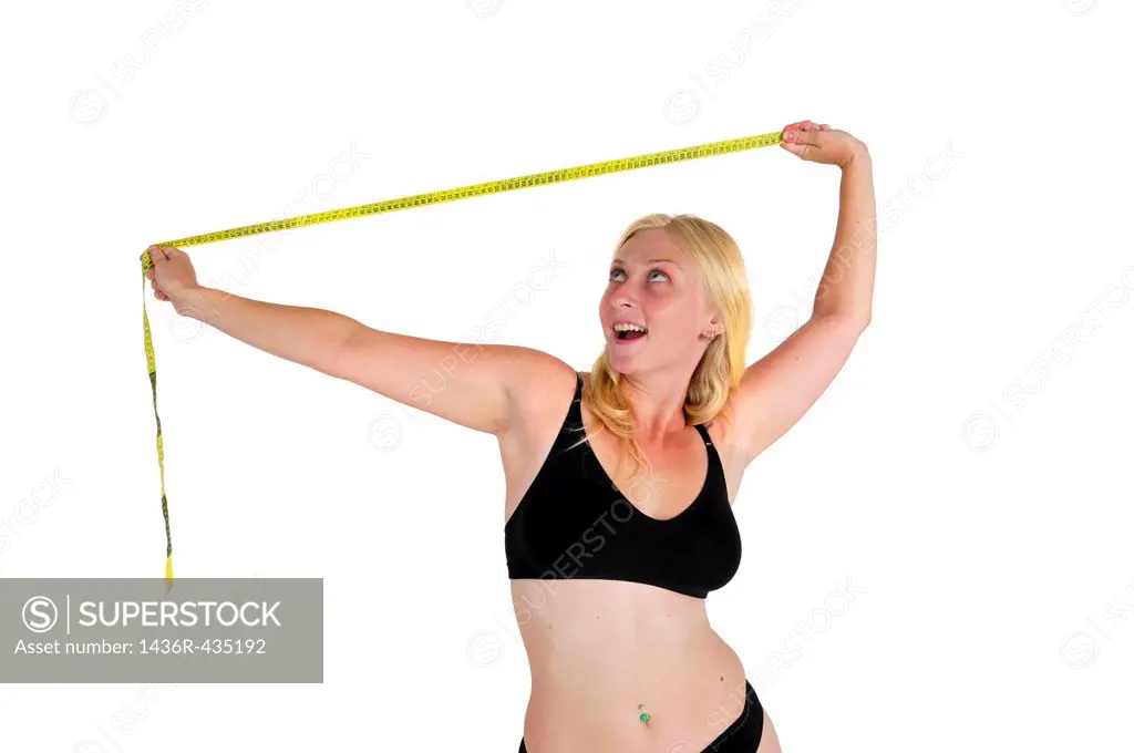 Young woman laughs at a tape measure  She has overcome compulsive body analysis caused by body image disorder such as anorexia nervosa
