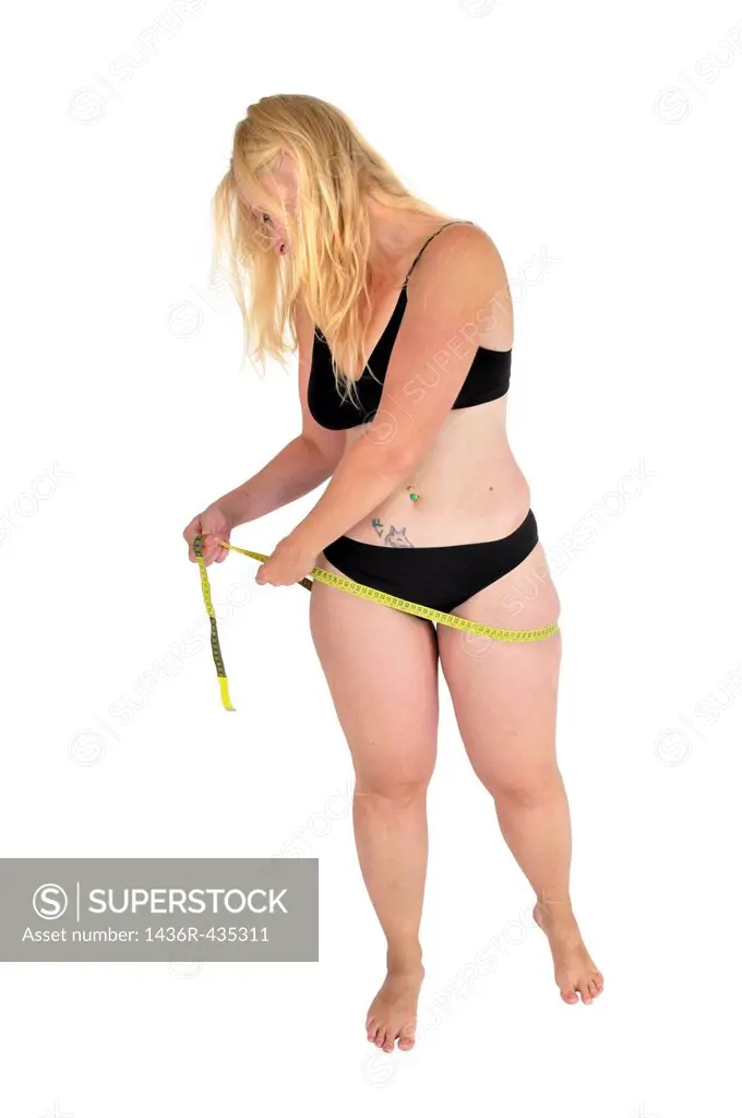 Eating disorder and body image young woman measures her hip with a tape measure  She may be keeping track of weight loss during a diet but compulsive ...