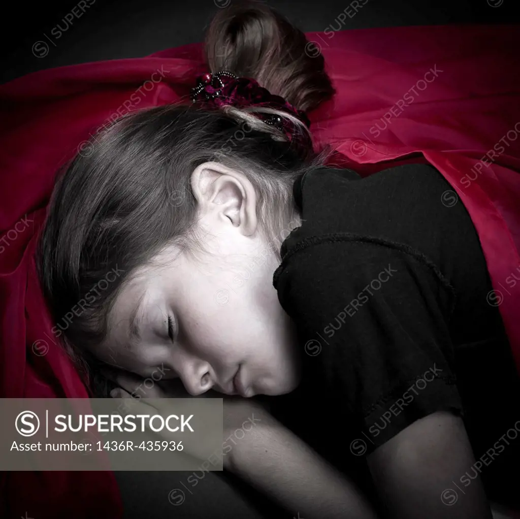 a girl is curled up asleep in a red cloth