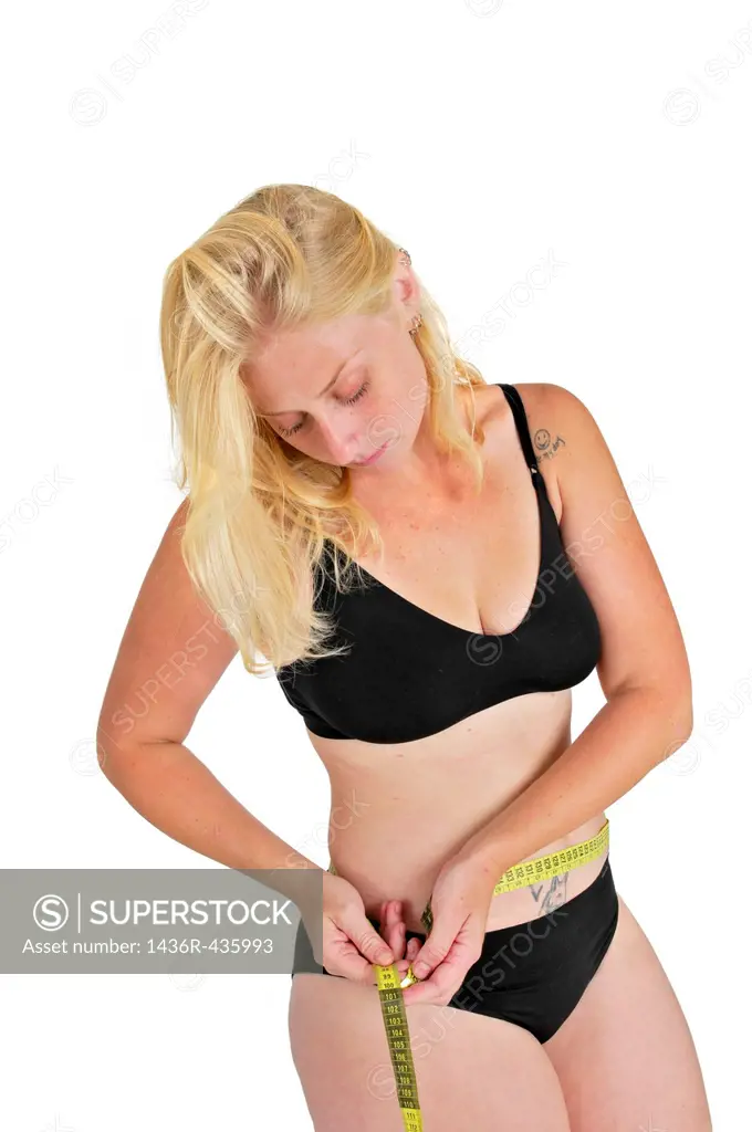 Eating disorder and body image young woman measures her hip with a tape measure  She may be keeping track of weight loss during a diet but compulsive ...