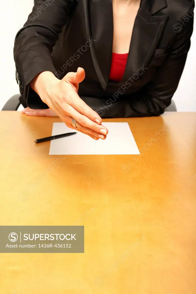 View of a business-woman sitting at a desk greeting with a blank paper infront