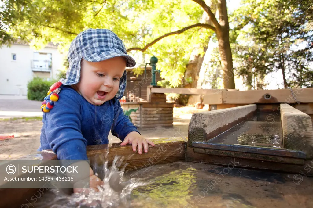 boy playing with water splashing, summer on playground