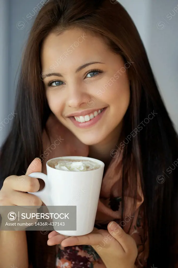 Beautiful young girl holding hot chocolate and smiling in front of the camera