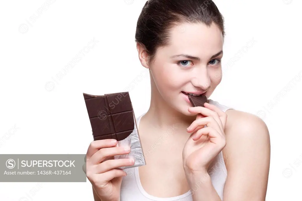 Beautiful young woman eating dark chocolate