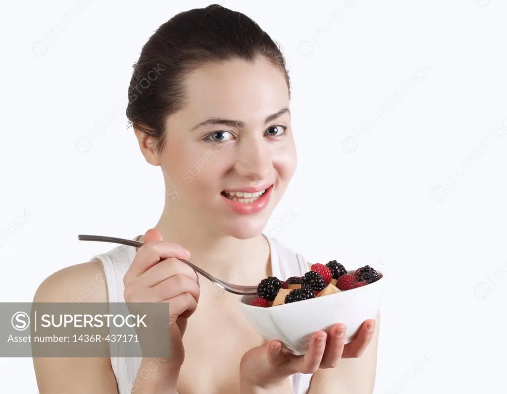 Beautiful young woman eating fruit salad
